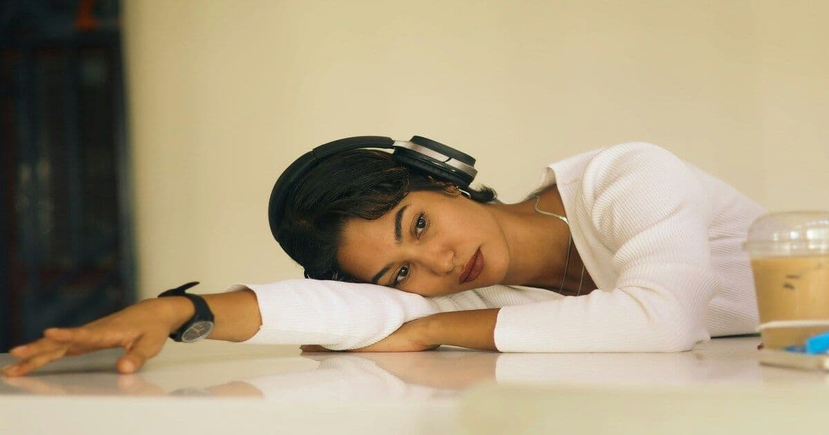 A young Nigerian woman resting her head on a table, looking emotionally drained and exhausted
