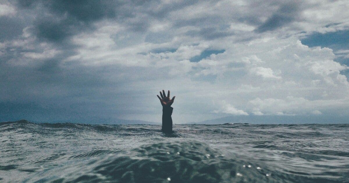 Hand reaching out from the ocean, symbolizing struggle, seeking help, and the journey toward emotional resilience.