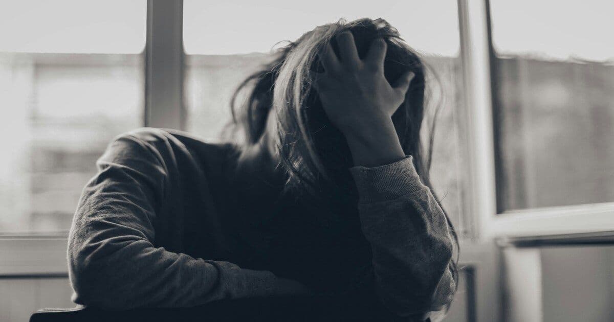 A woman runs her hand through her hair and touches her face, reflecting moments of stress, contemplation, or emotional overwhelm.