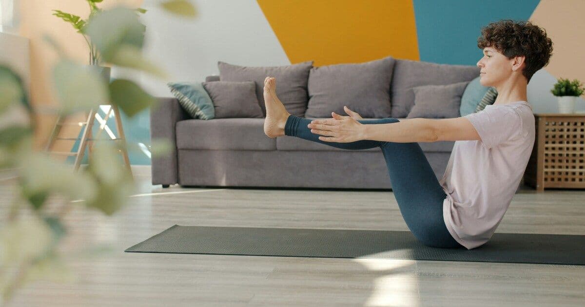 A person practicing yoga indoors, stretching gently on a mat to relieve stress and relax the body.