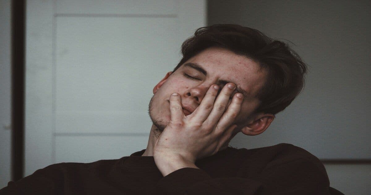 Young man with eyes closed and hand over his face