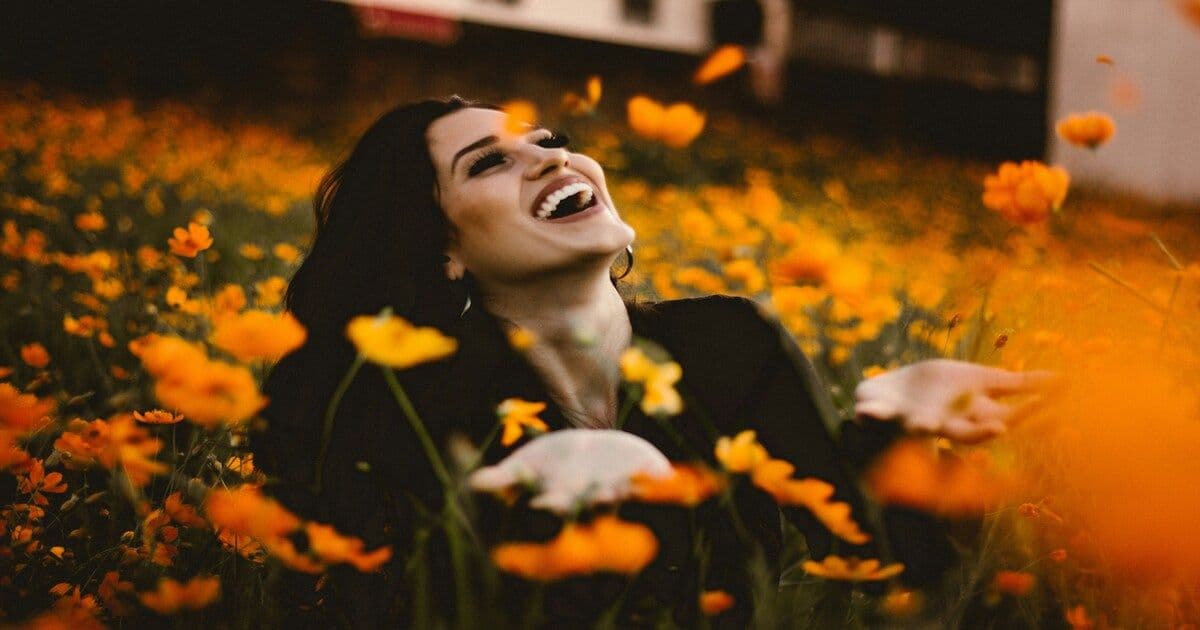 A joyful woman standing or twirling in a field of colorful blooming flowers, smiling naturally
