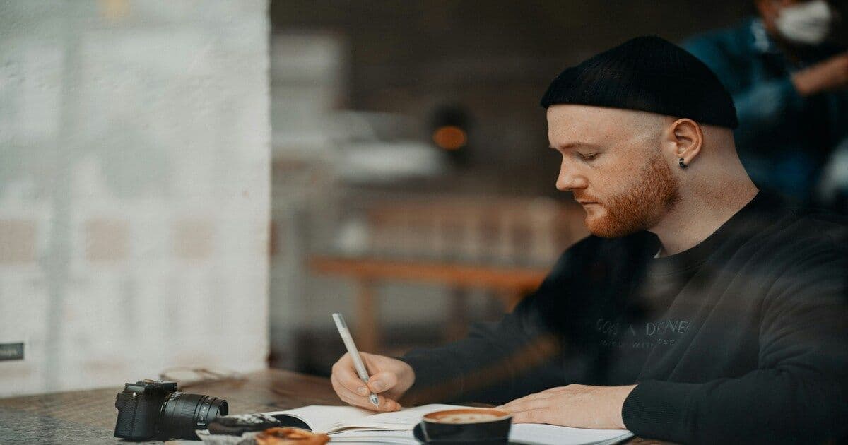 man writing in notebook