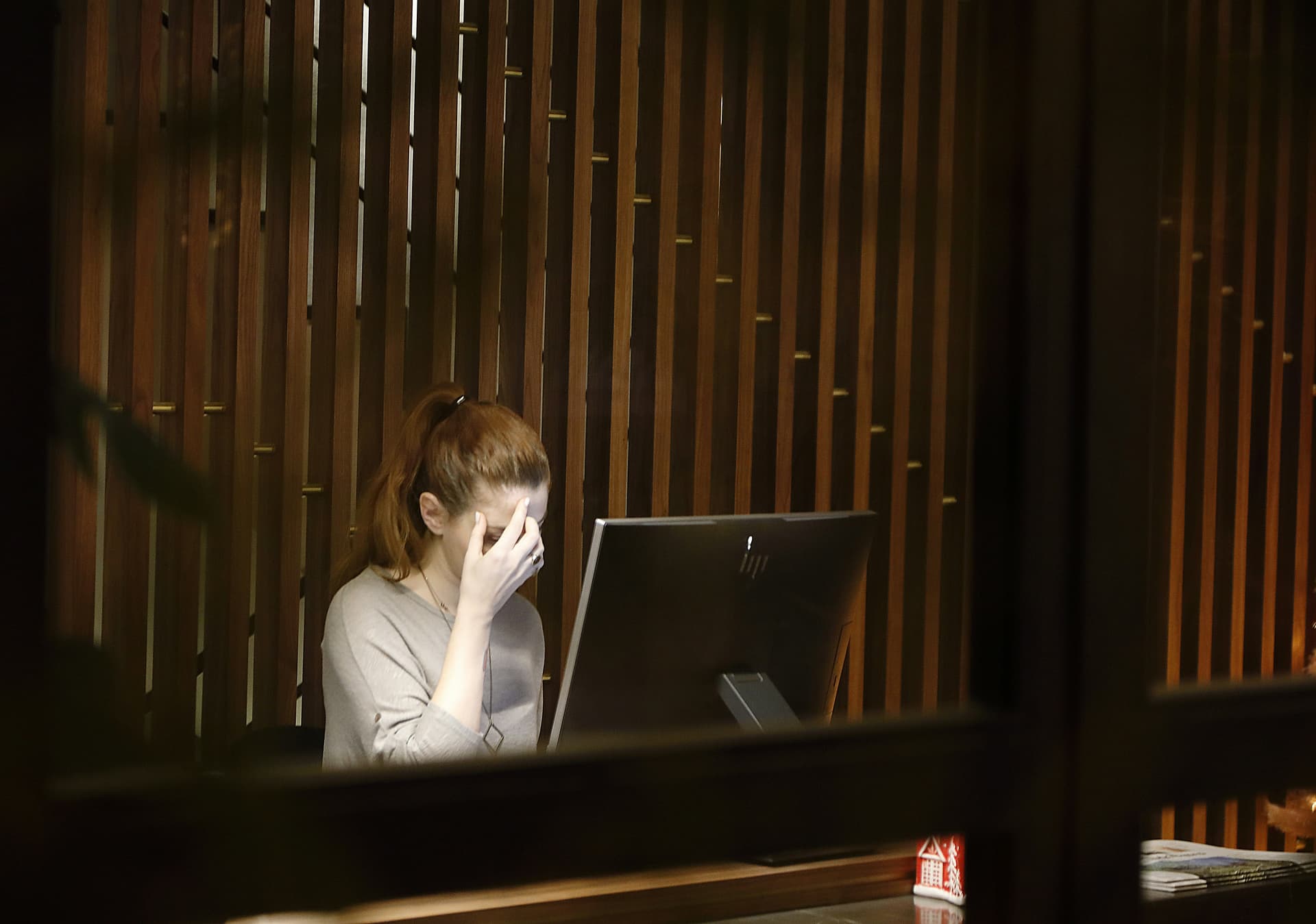 A young adult sitting with hands pressing their temples, eyes closed, showing discomfort and tension, reflecting headache caused by stress or anxiety.